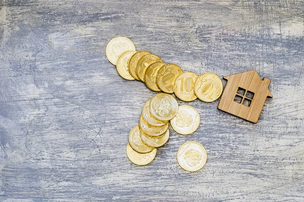 Imitation of a house with metal ten-ruble coins of Russia on a scratched background under the concrete.