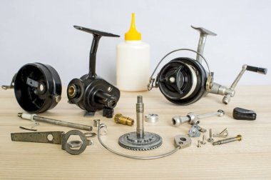 A fishing spinning reel as a whole and a second similar completely disassembled. Concept: parts of a whole. clipart