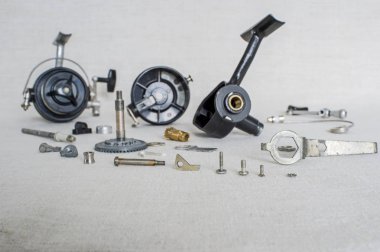 A fishing spinning reel as a whole and a second similar completely disassembled. Concept: parts of a whole. clipart