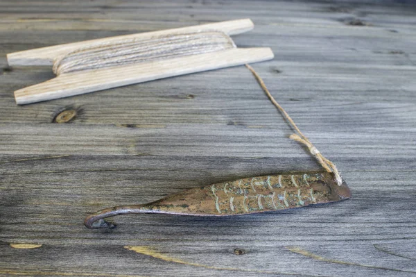 Antické řešení pro vertikální blikání dravých ryb. Měděný kužel a cívka s provazem na dřevěném pozadí. — Stock fotografie