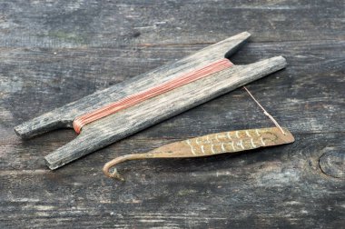 Eski dikey yanıp sönen yırtıcı balık için mücadele. Bakır dövme Spinner ve ahşap rustik arka planda ip ile reel