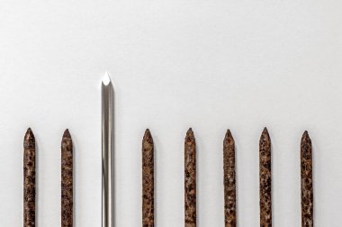 Metal parlak keskin çivi hafif bir arka plan üzerinde eski paslı çivi bir satır da öne çıkmaktadır.