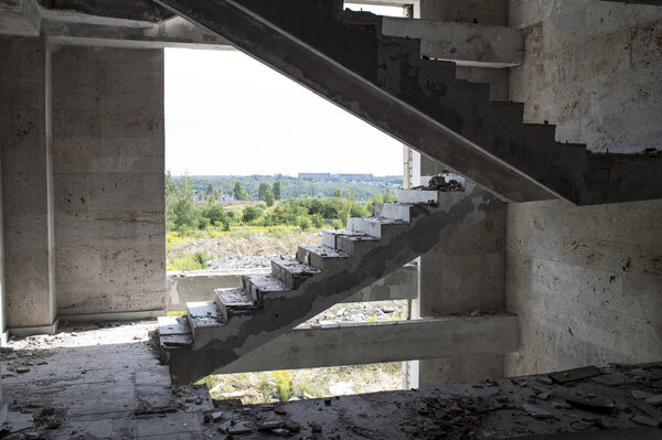 The staircase of the destroyed large building at a height against the sky and the natural landscape