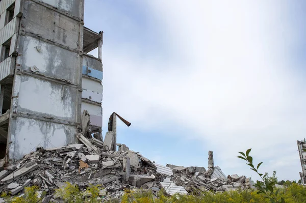 A pile of concrete debris with the remains of a large building against the blue sky. Background. Text space