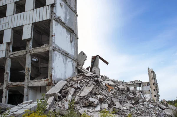 A pile of concrete debris with the remains of a large building against the blue sky. Background. Text space