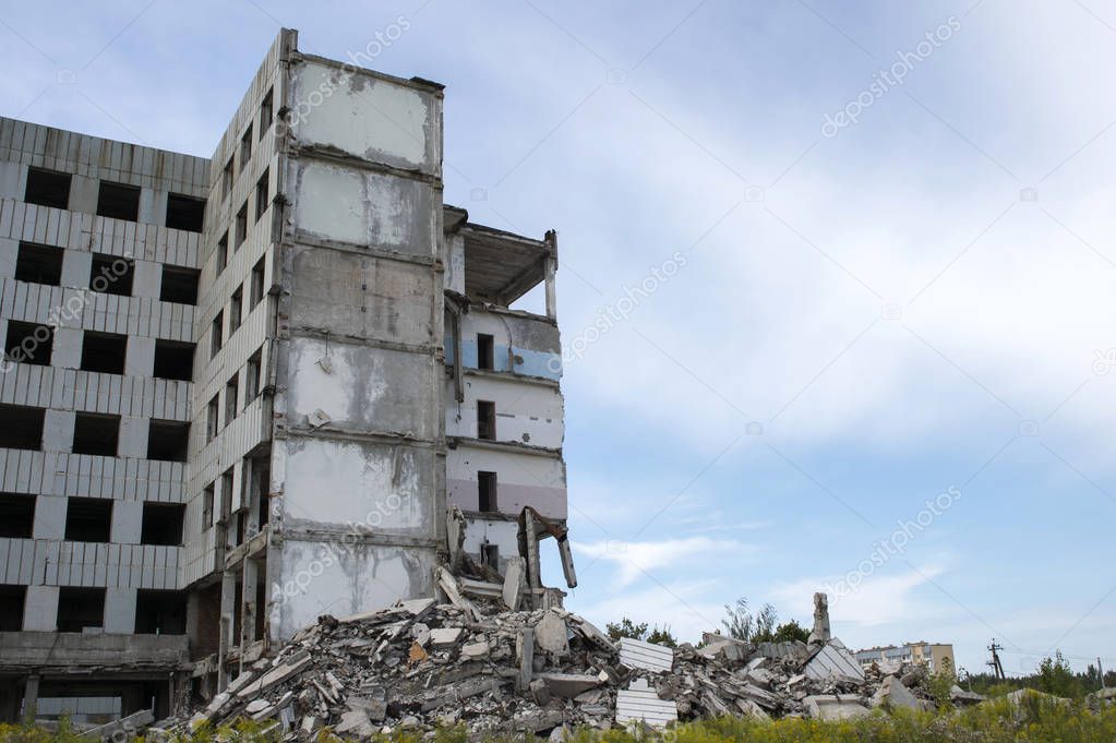 A pile of concrete debris with the remains of a large building against the blue sky. Background. Text space