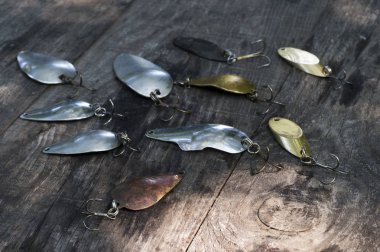 Bir vintage ahşap arka plan üzerinde bir yırtıcı yakalamak için farklı renklerde bir kaşık şeklinde Metal spinners.