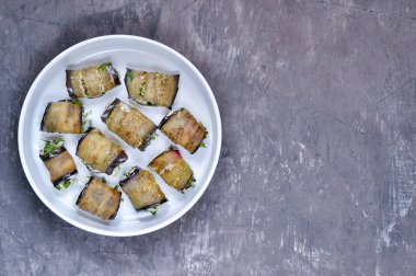 Beyaz bir tabak tabaktabak ceviz, krema, sarımsak, peynir ve kişniş yeşillikleri ile doldurulmuş kızarmış patlıcan tabak rulo.