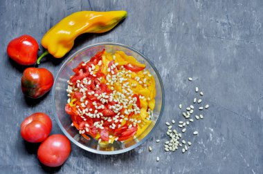 Kırmızı ve sarı tatlı biber, bir vintage sefil gri arka plan üzerinde bir cam salata kase domates