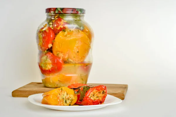 Stuffed vegetables pickled red and yellow peppers lie on a white