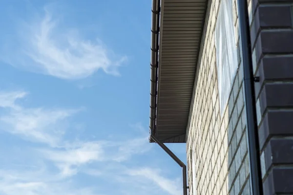 Das Dach der Ecke des neuen Hauses mit einer Entwässerungsanlage gegen den blauen Himmel. Hintergrund — Stockfoto