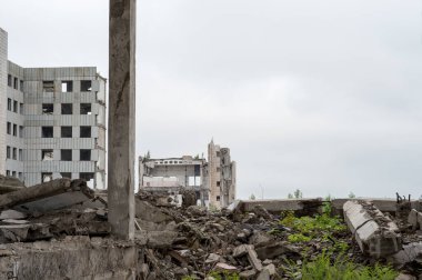 Gri gökyüzüne karşı beton enkaz ve kirişlerle büyük bir binayı yıktılar. Yıkım konsepti. Arkaplan.