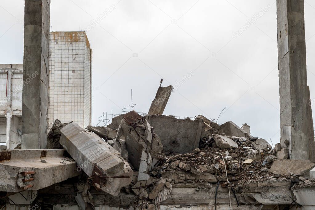 Large grey concrete fragments of a building with a lying beam in the foreground and a concrete slab sticking up into the sky. The concept of destruction. Background.