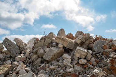 Mavi gökyüzüne karşı yıkılan bir binanın beton parçaları.