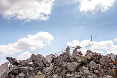 Mavi gökyüzüne dayanan beton demirle yıkılmış bir binanın beton parçaları. Arkaplan