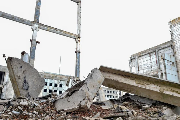 Gebroken betonnen platen en balken op de achtergrond van een verwoest gebouw en grijze lucht. Achtergrond — Stockfoto