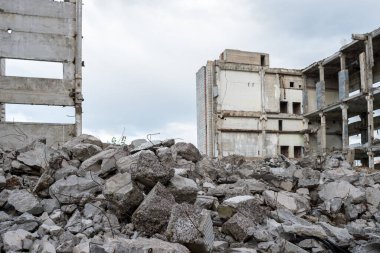 Yıkılan binanın arka planında beton döküntüler ve gri bir gökyüzü. Arkaplan.