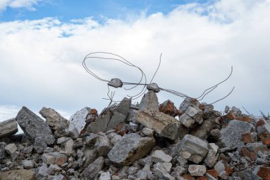 Yıkılmış bir binanın kalıntılarının beton parçaları gri bulutlu mavi gökyüzüne karşı. Arkaplan