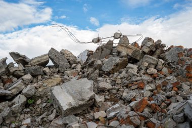 Yıkılmış bir binanın kalıntılarının beton parçaları gri bulutlu mavi gökyüzüne karşı. Arkaplan