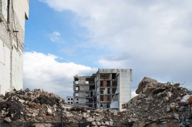 Beton döküntüler ve ön planda çökmüş bir duvar büyük bir binanın kalıntılarına karşı. Arkaplan.