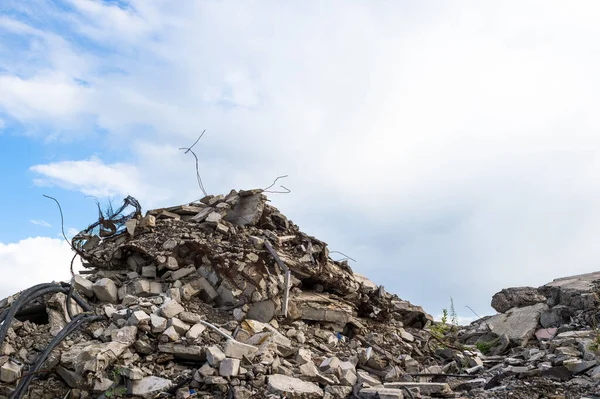 Betonnen fragmenten van de resten van een verwoest gebouw tegen een blauwe lucht met grijze wolken. Achtergrond — Stockfoto