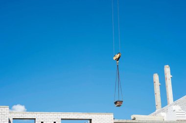 Kase çözeltisi vinci gökyüzündeki beton kirişlerin arka planında bir tuğla ev yapımında besleyin. Geçmişi. Ceset yok..