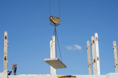 Yazın mavi gökyüzü ve bulutlara karşı, Rusya, Kursk bölgesi, Zheleznogorsk, Ağustos 2018 'de inşa edilmiş çok katlı bir binanın inşasında çalışan işçi..