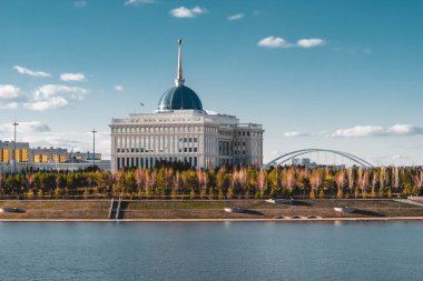 Astana, Kazakistan'ın nehrin karşısındaki mavi gökyüzü ile Cumhurbaşkanlığı Sarayı 