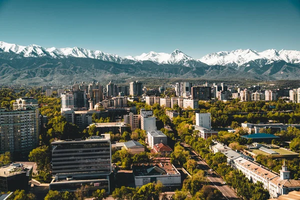 Město krajina na pozadí zasněžené vrcholky pohoří Tian Shan v Almaty Kazachstán — Stock fotografie