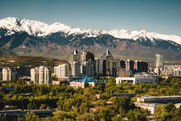 Město krajina na pozadí zasněžené vrcholky pohoří Tian Shan v Almaty Kazachstán — Stock fotografie