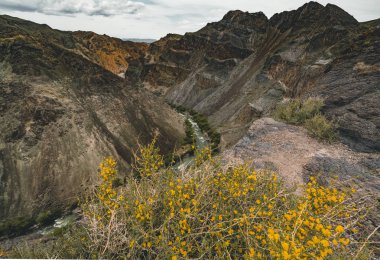 Çarın Kanyonu dağlar ve gökyüzü bulutlar ile Kazakistan'daki nehirde.