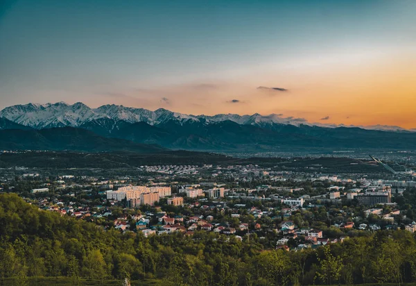 Puesta de sol sobre la ciudad de Almaty y una vista de la Torre de TV Kok Tobe — Foto de Stock