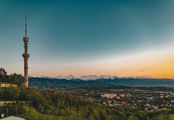 Pôr do sol sobre a cidade de Almaty e uma vista da Torre de TV Kok Tobe — Fotografia de Stock