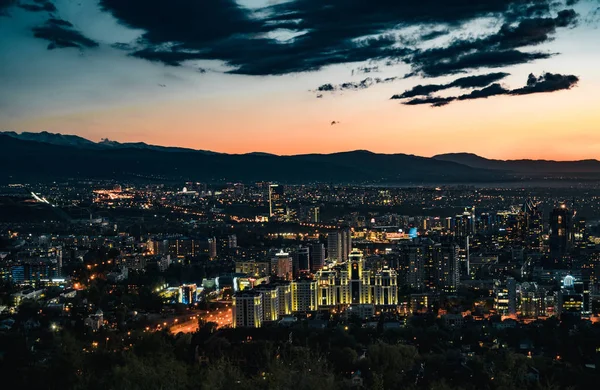 Puesta de sol sobre la ciudad de Almaty y una vista de la Torre de TV Kok Tobe — Foto de Stock