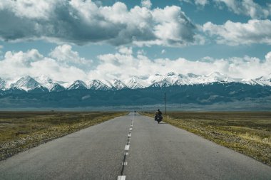 Motor bisikletçi Kazakistan Orta Asya bozkır Caddesi ile arka plan, Tian Shan dağlarında üzerinde