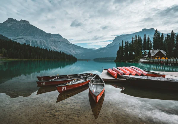 Los kayaks rojos se secan boca abajo. Lago Esmeralda en las Montañas Rocosas Canadienses con montañas y árboles y refelexión. Concepto de vacaciones activas y turismo — Foto de Stock