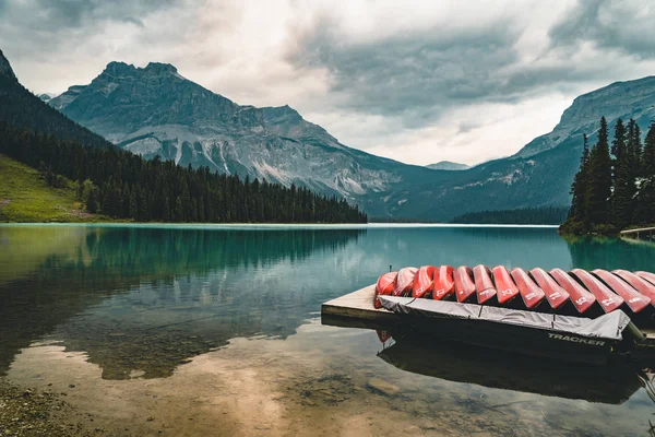 Los kayaks rojos se secan boca abajo. Lago Esmeralda en las Montañas Rocosas Canadienses con montañas y árboles y refelexión. Concepto de vacaciones activas y turismo — Foto de Stock