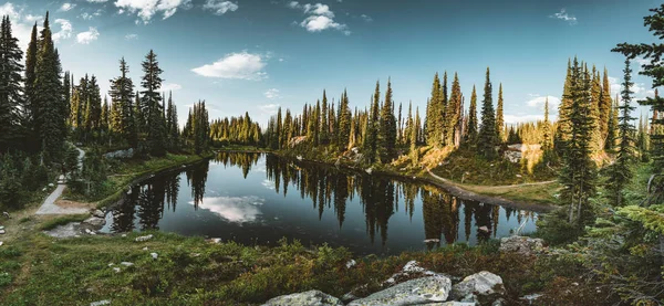 Vista do Lago no cume do Monte Revelstoke através da floresta com céu azul e nuvens. British Columbia Canadá . — Fotografia de Stock