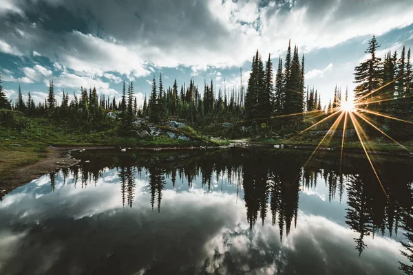 Tó a csúcs a Mount Revelstoke naplemente elmélkedés sunstar egész erdő kék ég és a felhők. British Columbia, Kanada. — Stock Fotó