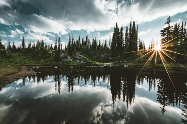 Lac sur le sommet du mont Revelstoke coucher de soleil réflexion étoile de soleil à travers la forêt avec ciel bleu et nuages. Colombie-Britannique Canada . — Photo