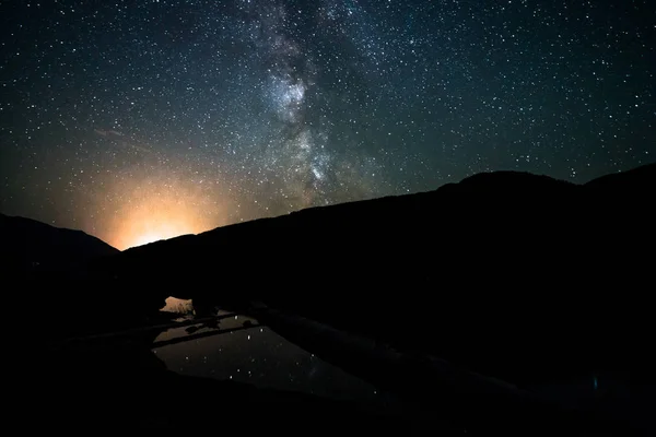 Melkweg melkwegstelsel nachtelijke hemel over kleine vijver met reflectie. Canada, Brits-Columbia. — Stockfoto