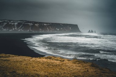 Ünlü siyah kum Beach Reynisfjara İzlanda'daki güneş doğarken. Rüzgarlı sabah. Okyanus dalgaları. Renkli gökyüzü. Sabah günbatımı.