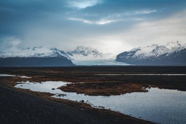 Yol büyük buzul ve İzlanda Vatnajokull buzul hava dron görüntü dağlarda doğru sokak otoyol ve bulutlar ve mavi gökyüzü ile lider. Dramatik kış sahne Vatnajokull Milli Parkı