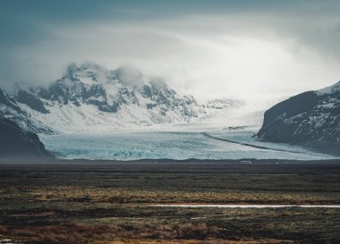 Yol büyük buzul ve İzlanda Vatnajokull buzul hava dron görüntü dağlarda doğru sokak otoyol ve bulutlar ve mavi gökyüzü ile lider. Dramatik kış sahne Vatnajokull Milli Parkı