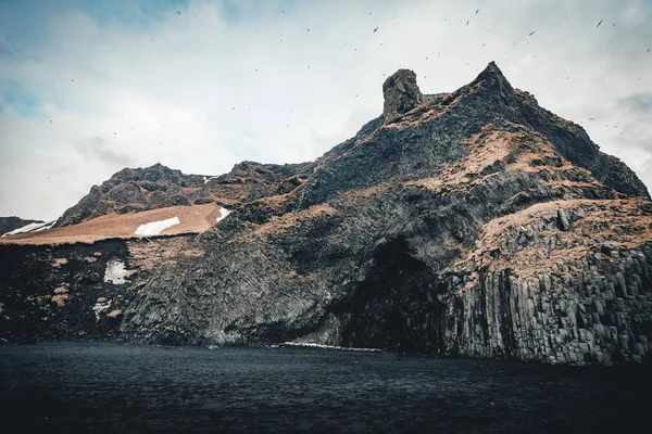 Reynisfjara siyah kum plaj ve dağ Reynisfjall, İzlanda. Rüzgarlı sabah. Okyanus dalgaları. Renkli gökyüzü. Sabah günbatımı.