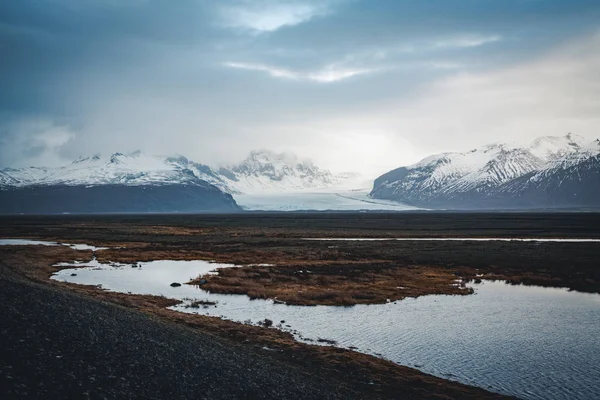 Camino que conduce hacia enormes glaciares y montañas en Islandia Vatnajokull imagen de avión no tripulado glaciar glaciar con carretera calle y nubes y cielo azul. Dramática escena invernal del Parque Nacional Vatnajokull — Foto de Stock