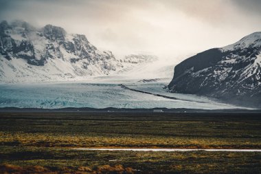 Yol büyük buzul ve İzlanda Vatnajokull buzul hava dron görüntü dağlarda doğru sokak otoyol ve bulutlar ve mavi gökyüzü ile lider. Dramatik kış sahne Vatnajokull Milli Parkı