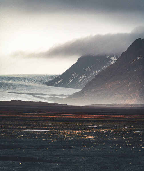 Road leading towards huge glacier and mountains in Iceland Vatnajokull glacier aerial drone image with street highway and clouds and blue sky. Dramatic winter scene of Vatnajokull National Park