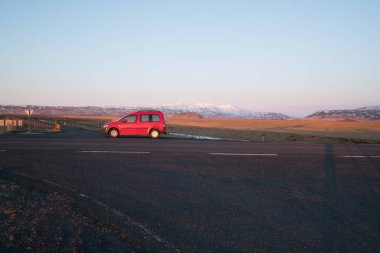 Borgarnes, İzlanda, Mayıs 2018: Kırmızı araba park akşam güneş ışığı sokakta.