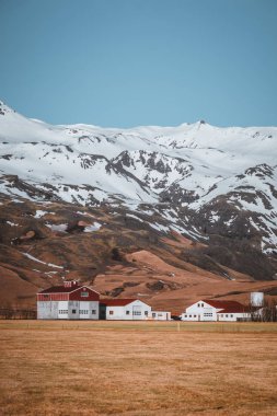 Kırmızı çatı South Iceland'deki / daki küçük köy dağlarda karşı beyaz ile tipik İzlanda manzara evleri.